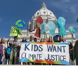 Children standing behind a sign that says "Kids want climate justice."